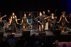 R&B band singers and musicians line the front of the stage to perform at the SEC