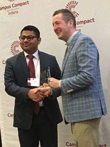 Eric Mejia is presented with an award from IN Campus Compact