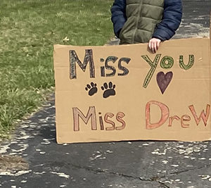 message written on cardboard says Miss you Miss Drew