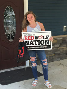 young woman holds Red Wolf Nation sign