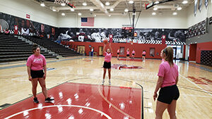 basketball players lined around the free throw lane in pink t-shirts one player shooting the ball